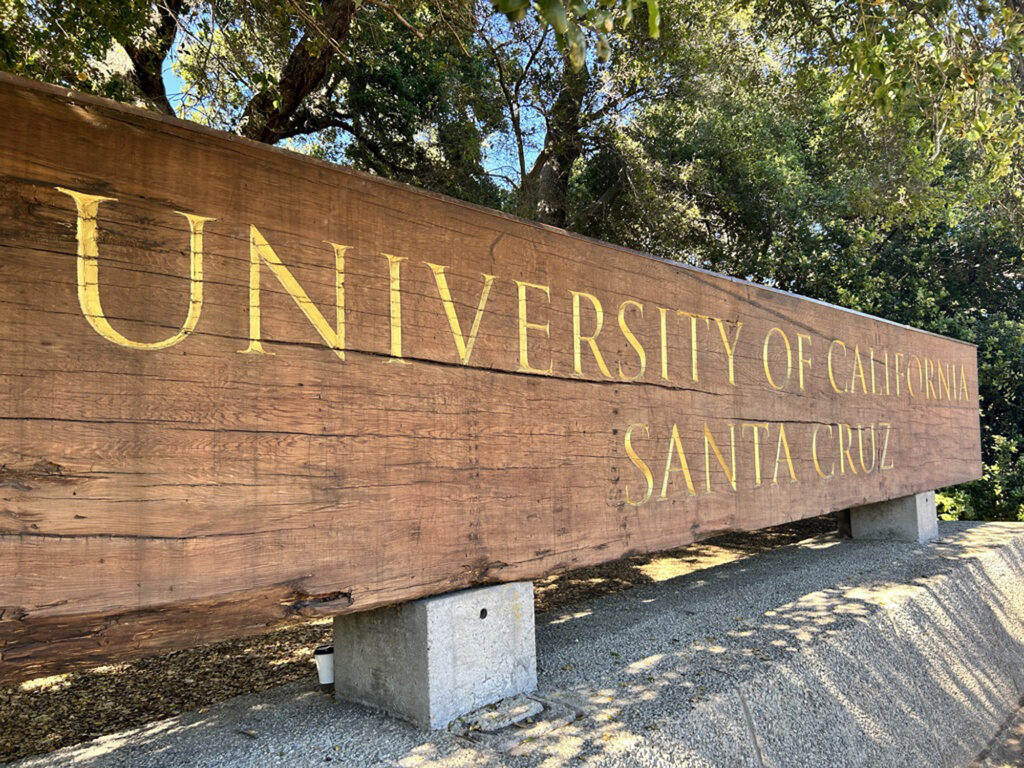 Wooden sign with the words, University of California, ɬֱ Cruz